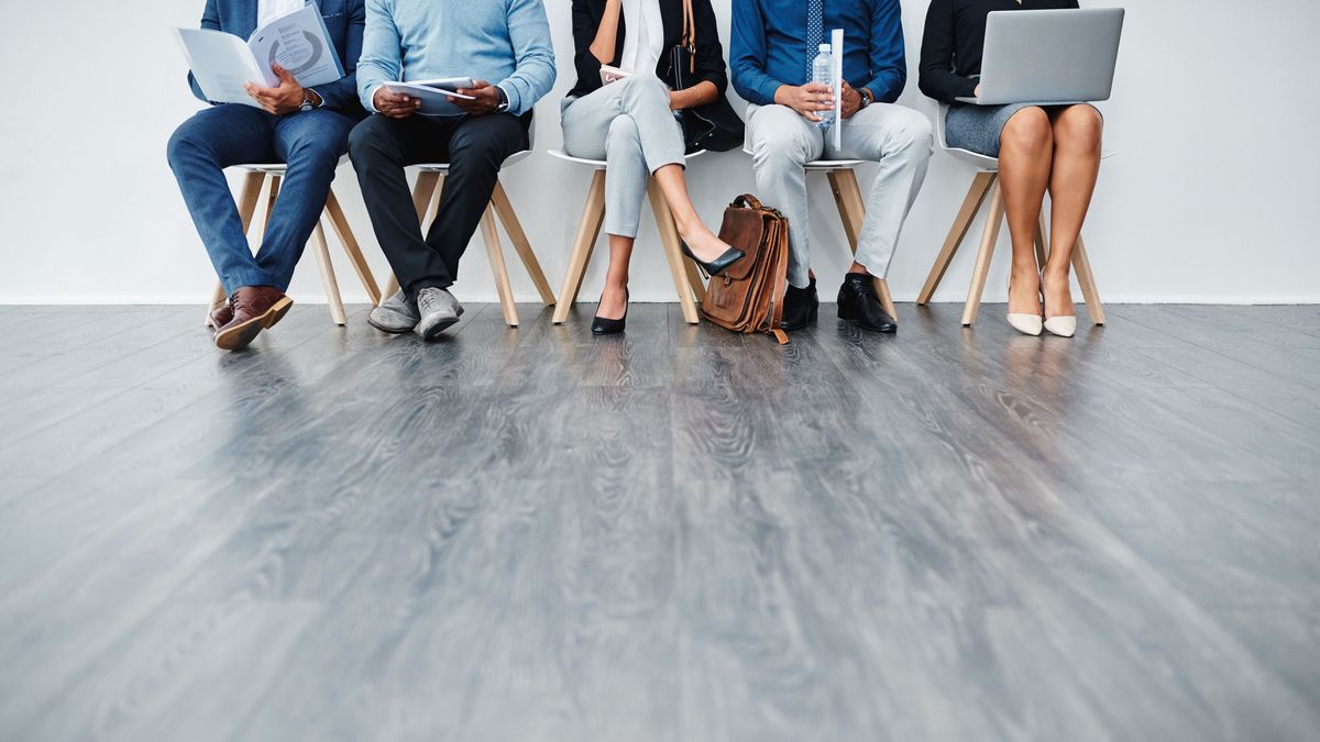 A cropped photo showing the legs of a line of business people sat in chairs