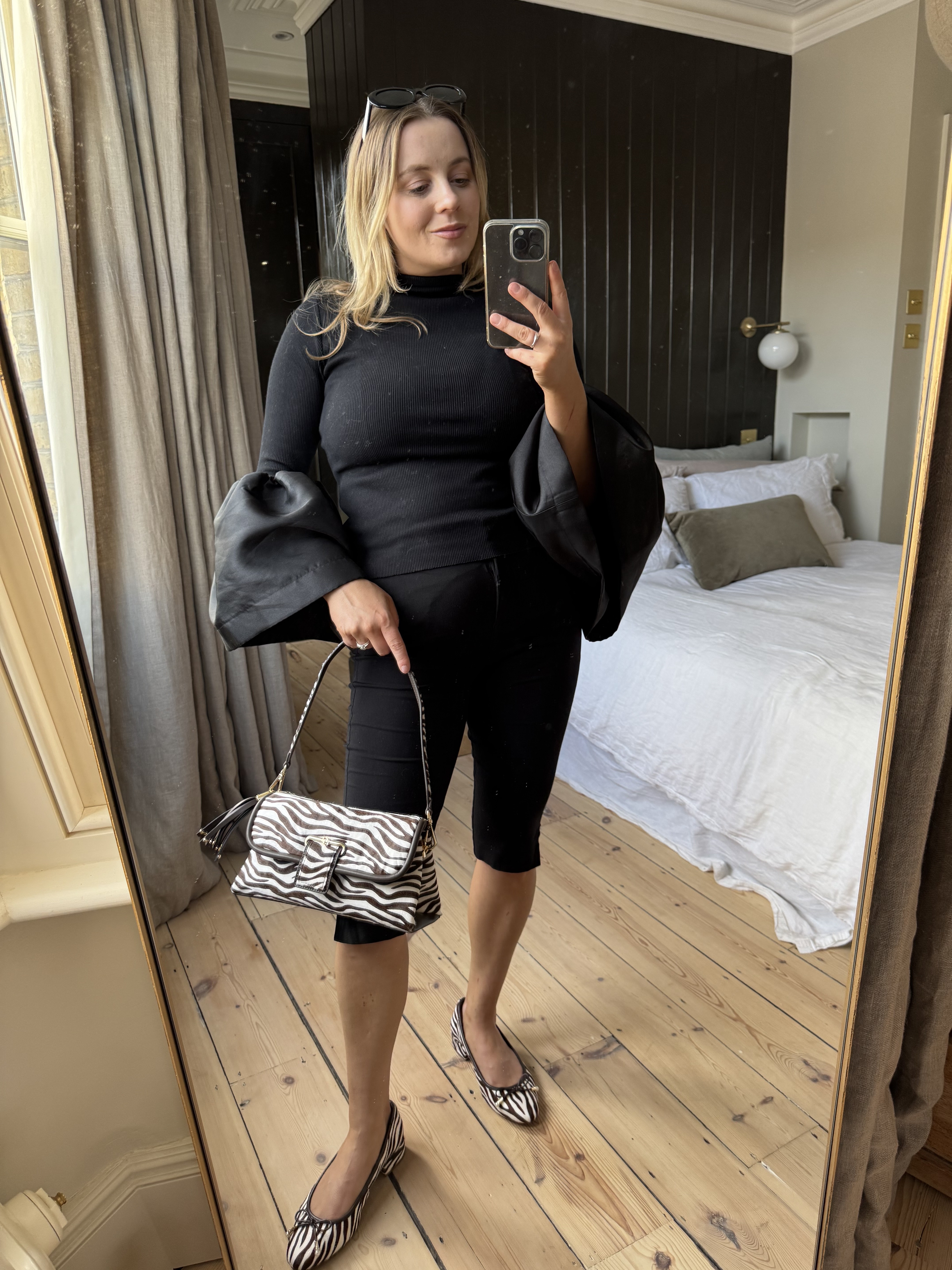 Girl in bedroom wearing zebra print shoes taking mirror selfie