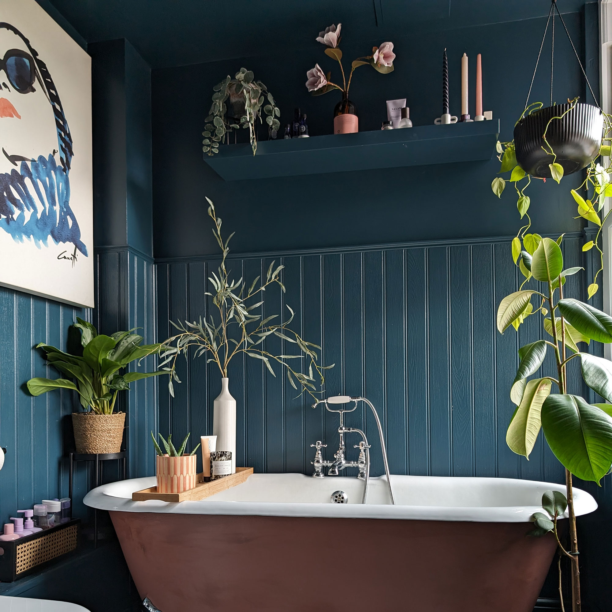 Teal bathroom with wall panelling, floating shelf, oversized artwork and terracotta painted freestanding bath