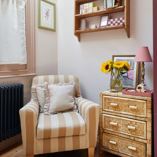 Pink striped armchair next to chest of drawers in a nursery