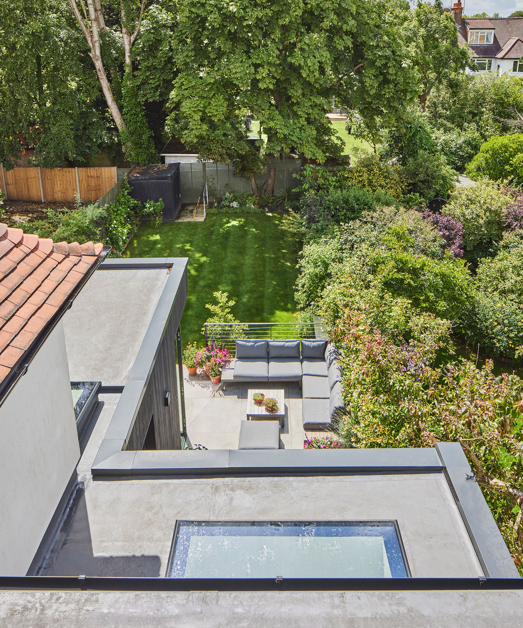 View out of a loft conversion onto a flat roof kitchen extension and bright patio and lawn