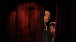 Louis de Pointe du Lac (Jacob Anderson) and Claudia (Delainey Hayles) peer out from behind a red velvet curtain that bears a projection of Lestat de Lioncourt's (Sam Reid) face in Interview with the Vampire season 2