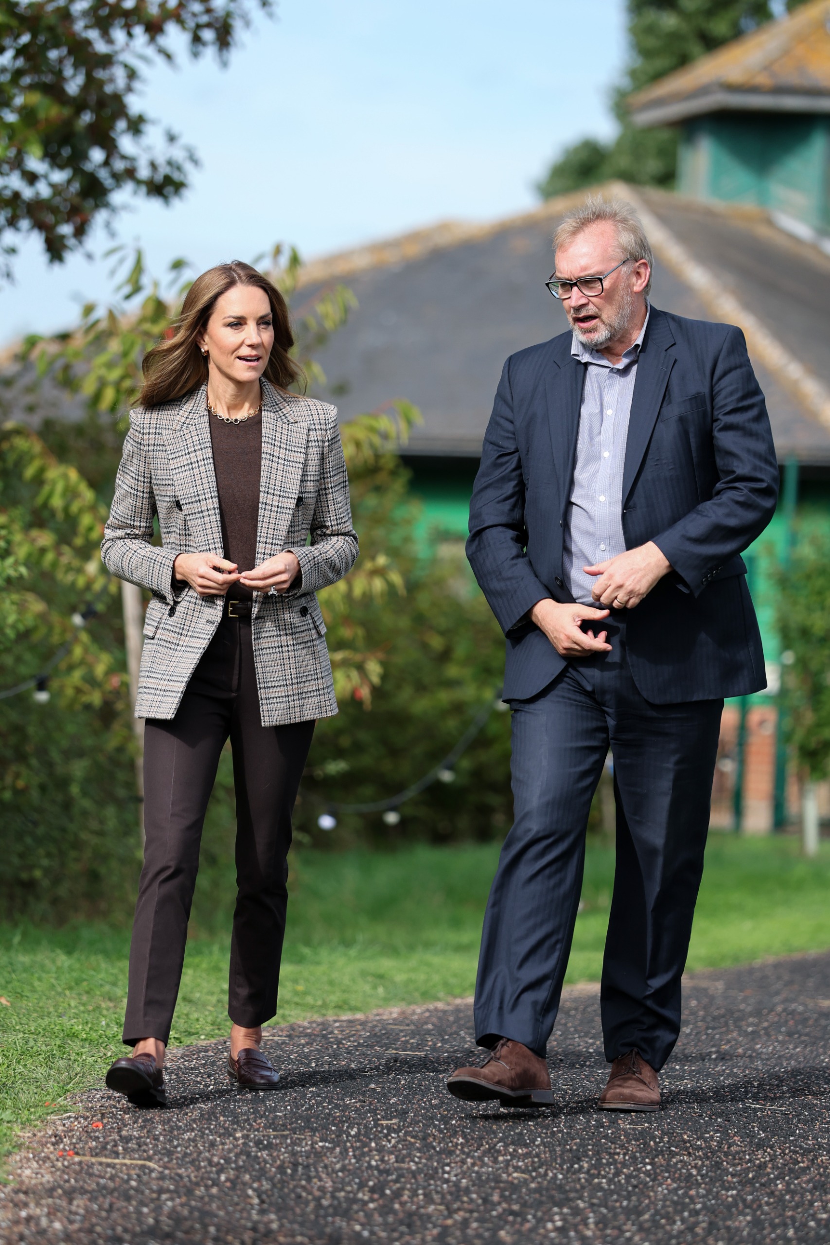 Princess Kate in a blazer and pants walking with the CEO of the Forward Trust outside