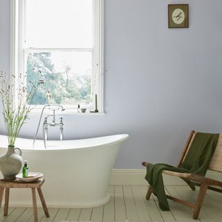 colour ideas for cottage style bathroom, pale lilac bathroom with artwork, stool, wood and rattan chair, bateau bath