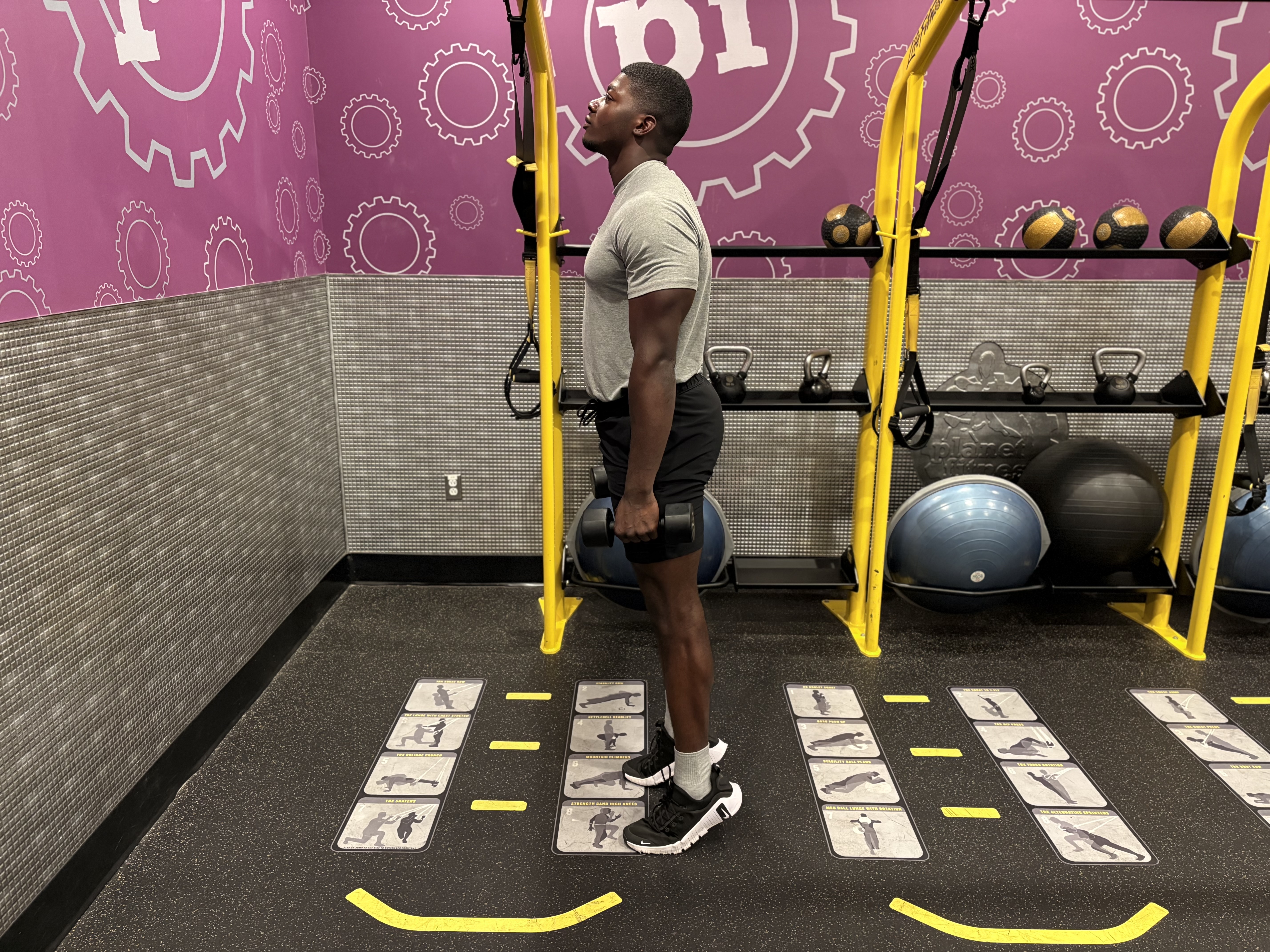 Man demonstrates a dumbbell exercise in a gym