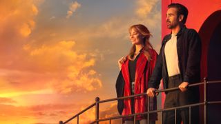 L-R: Margot Robbie and Colin Farrell stand looking out at a sunset in a promotional still for "A Big Bold Beautiful Journey"