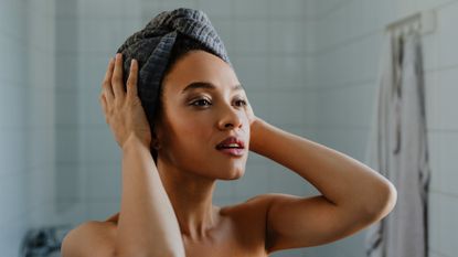 A portrait of a young woman after washing her hair, with a towel wrapped over her head.