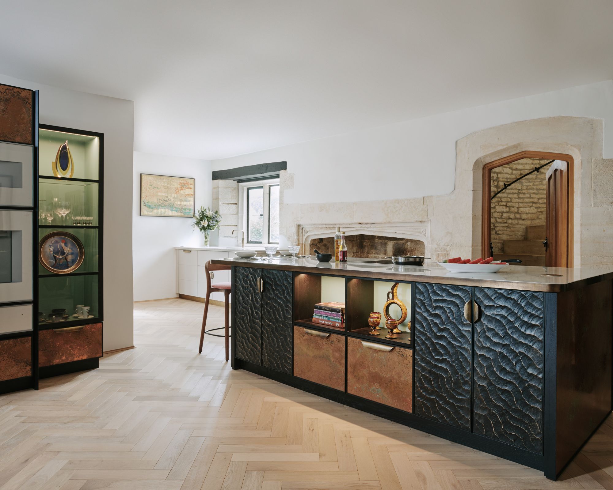 A textured black kitchen island stands in the middle of a historic home