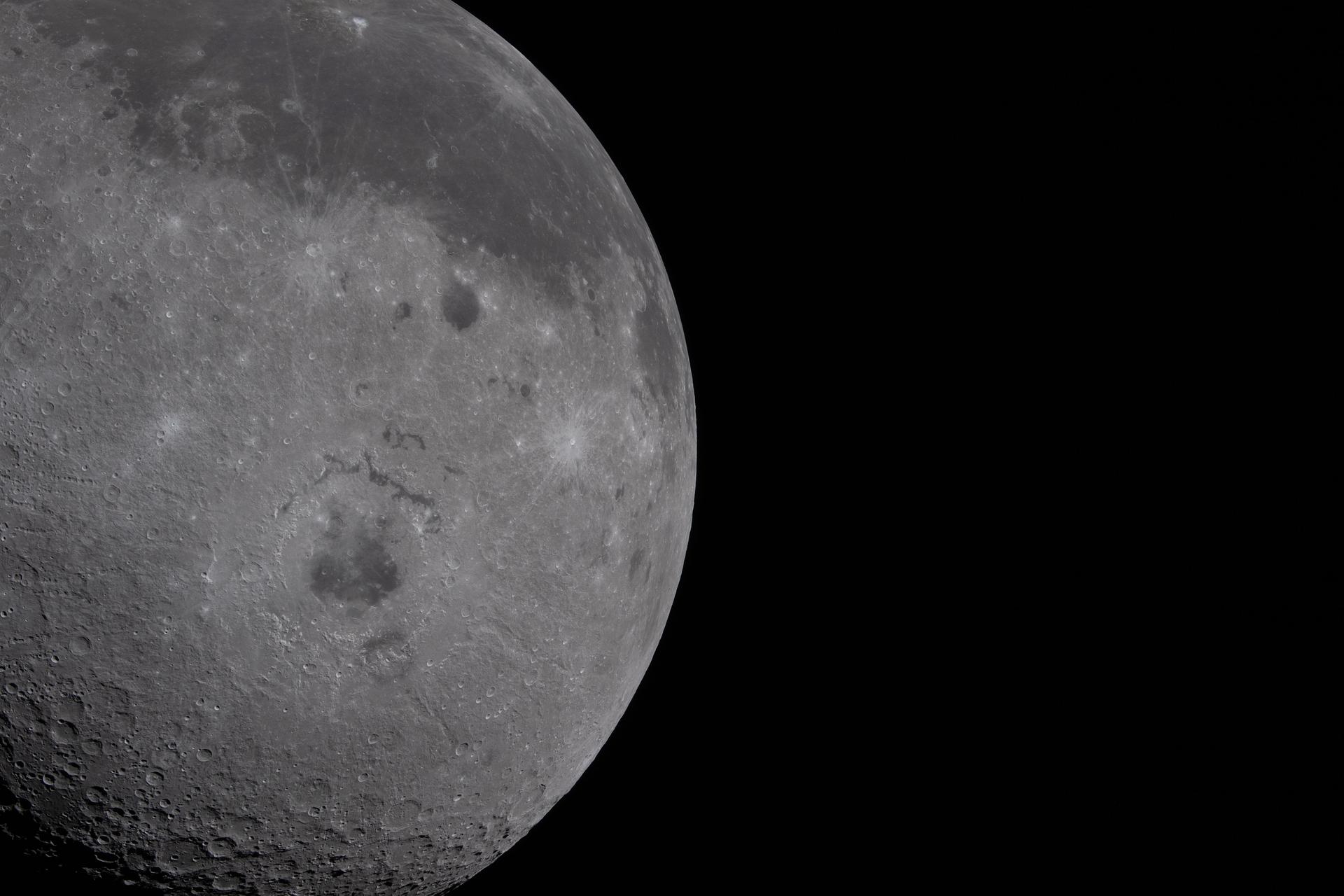 The moon fills half the frame, showing both the Earth-facing side and dark side of the moon