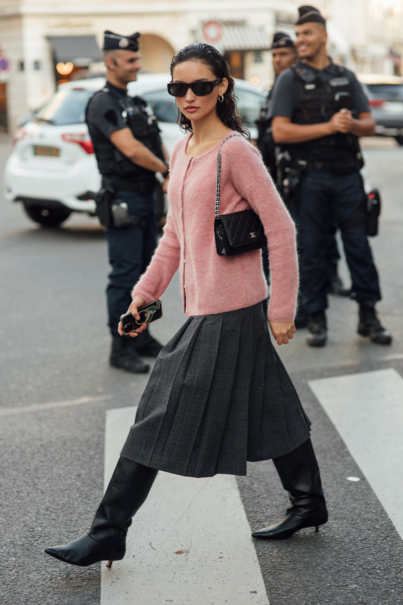 Woman in pale pink sweater, gray skirt and black boots