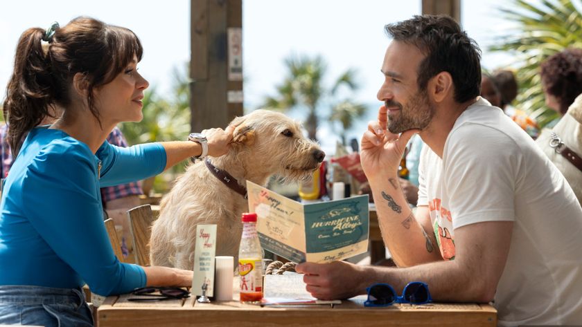 L-R: Anna (Zooey Deschanel), Merv the dog and Russ (Charlie Cox) sit together at a restaurant table in a scene from Prime Video&#039;s &quot;Merv&quot;