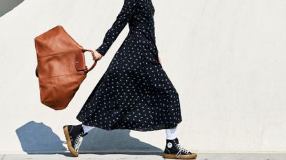 woman in a dress carrying a bag and wearing sneakers to work