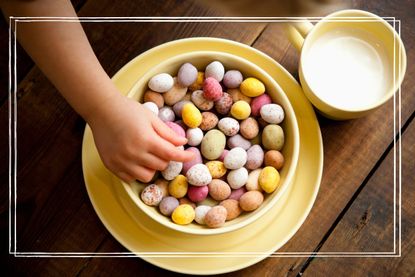 A child's hand reaching into an enormous bowl of mini eggs beside a glass of milk