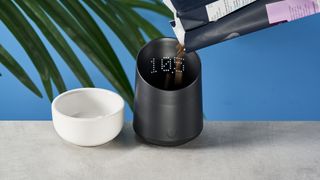 a black plastic coffee doser with an aesthetically pleasing design and a curved built-in LED screen