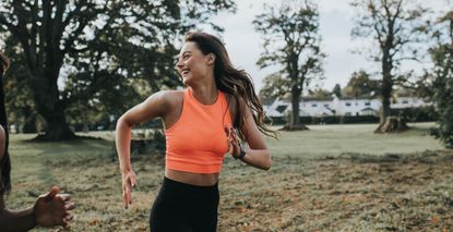 Single woman jogging through a park in the morning. She glances over her shoulder and laughs. How many days a week should I work out