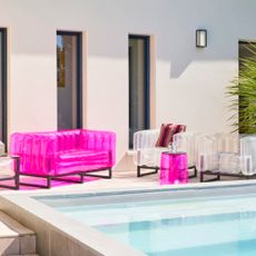 Mojow Yomi 151cm Wide Outdoor Patio Sofa with Cushions in pink with coordinating clear armchairs by a pool