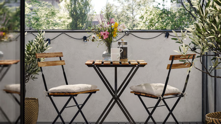 a bistro set on a small patio with lots of foliage in the scene