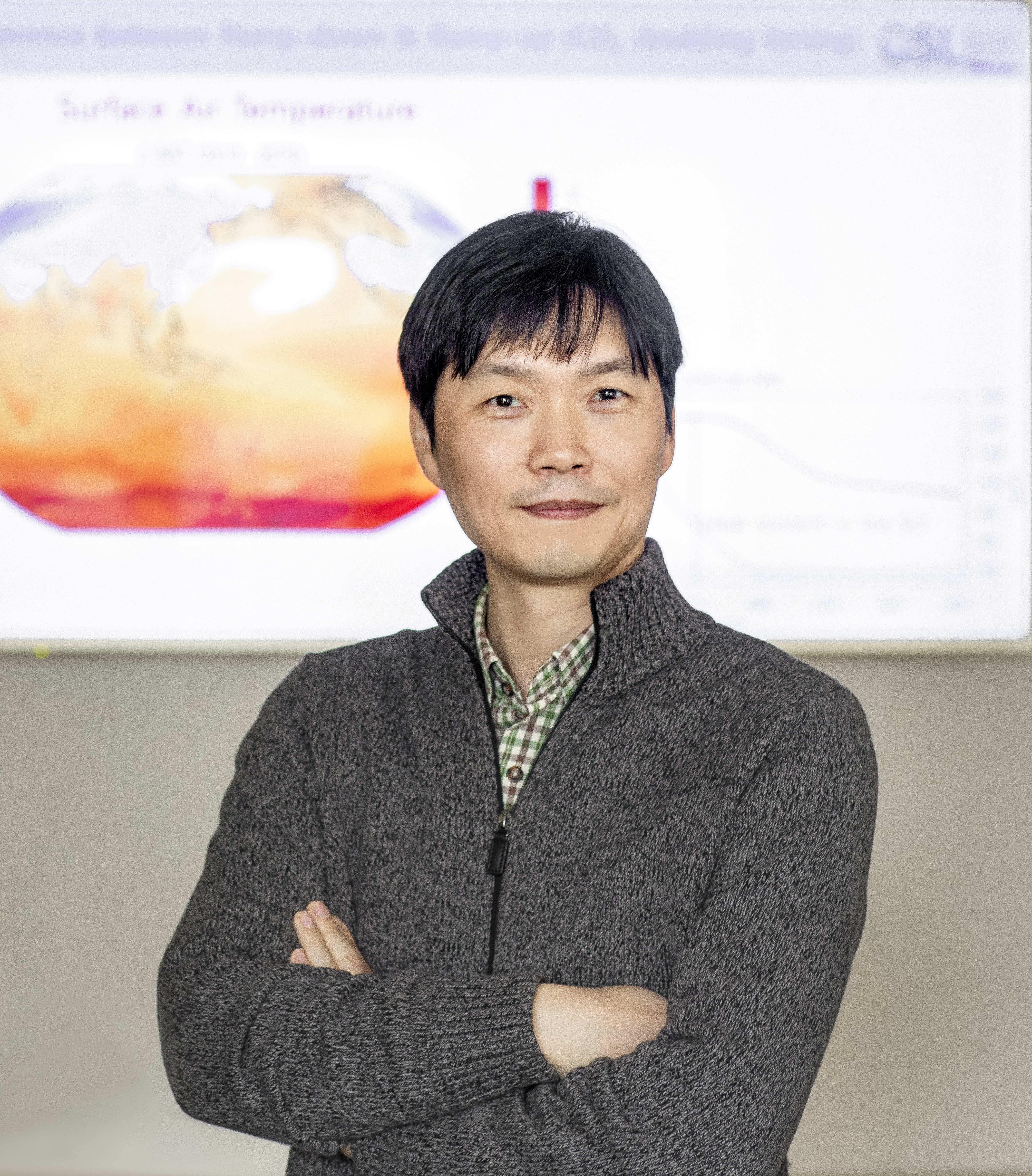 A photo of Jong-Seong Kug standing in front of a whiteboard displaying climate research.