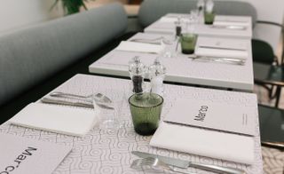 Close up shot showing white tables set with cutlery & menus