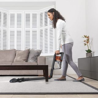 A woman using a Shark IZ300UK to clean a living room rug