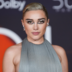Florence Pugh wearing slicked back hair and graphic eyeliner stickers.