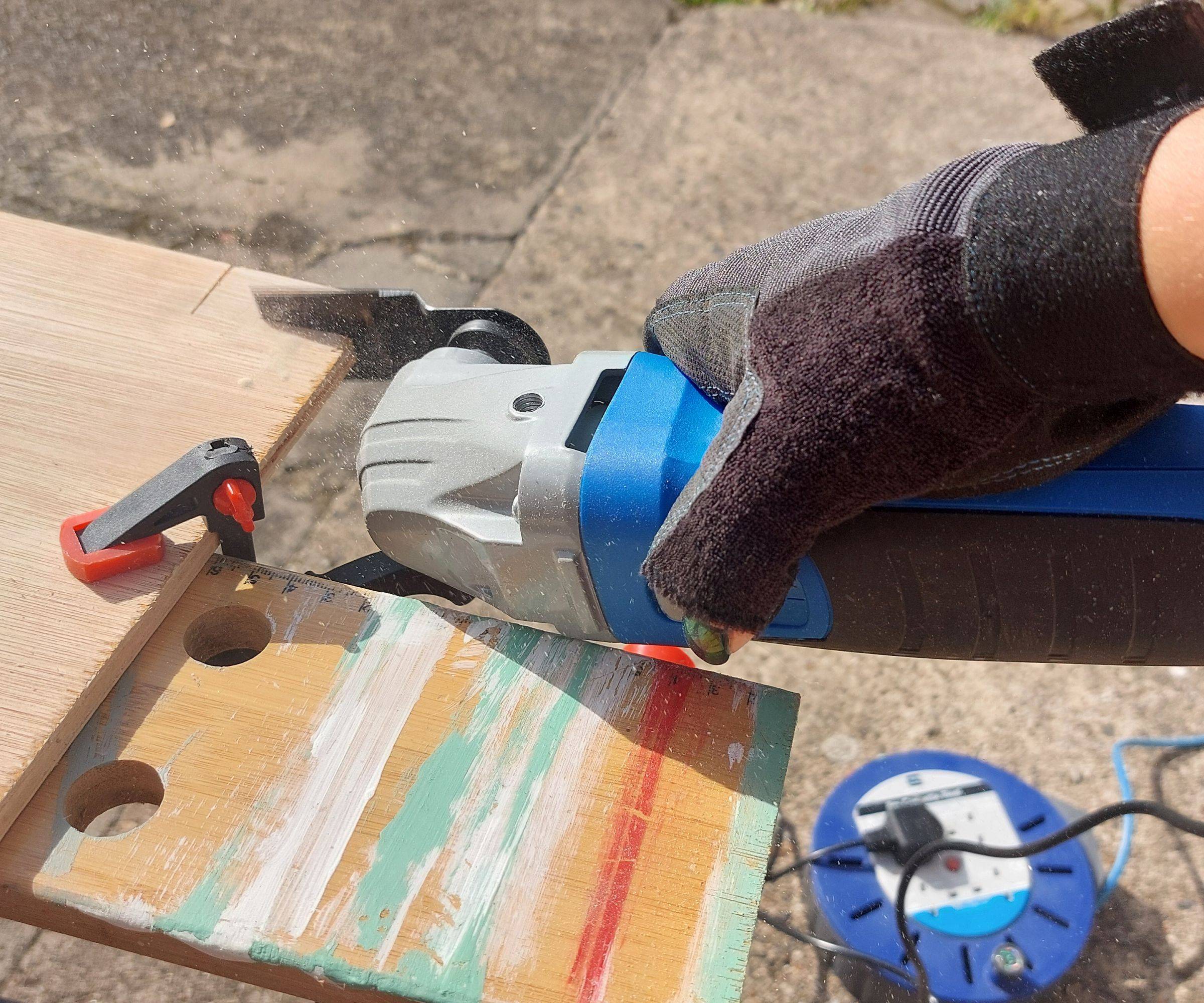 A multitool cutting a piece out of a wooden board