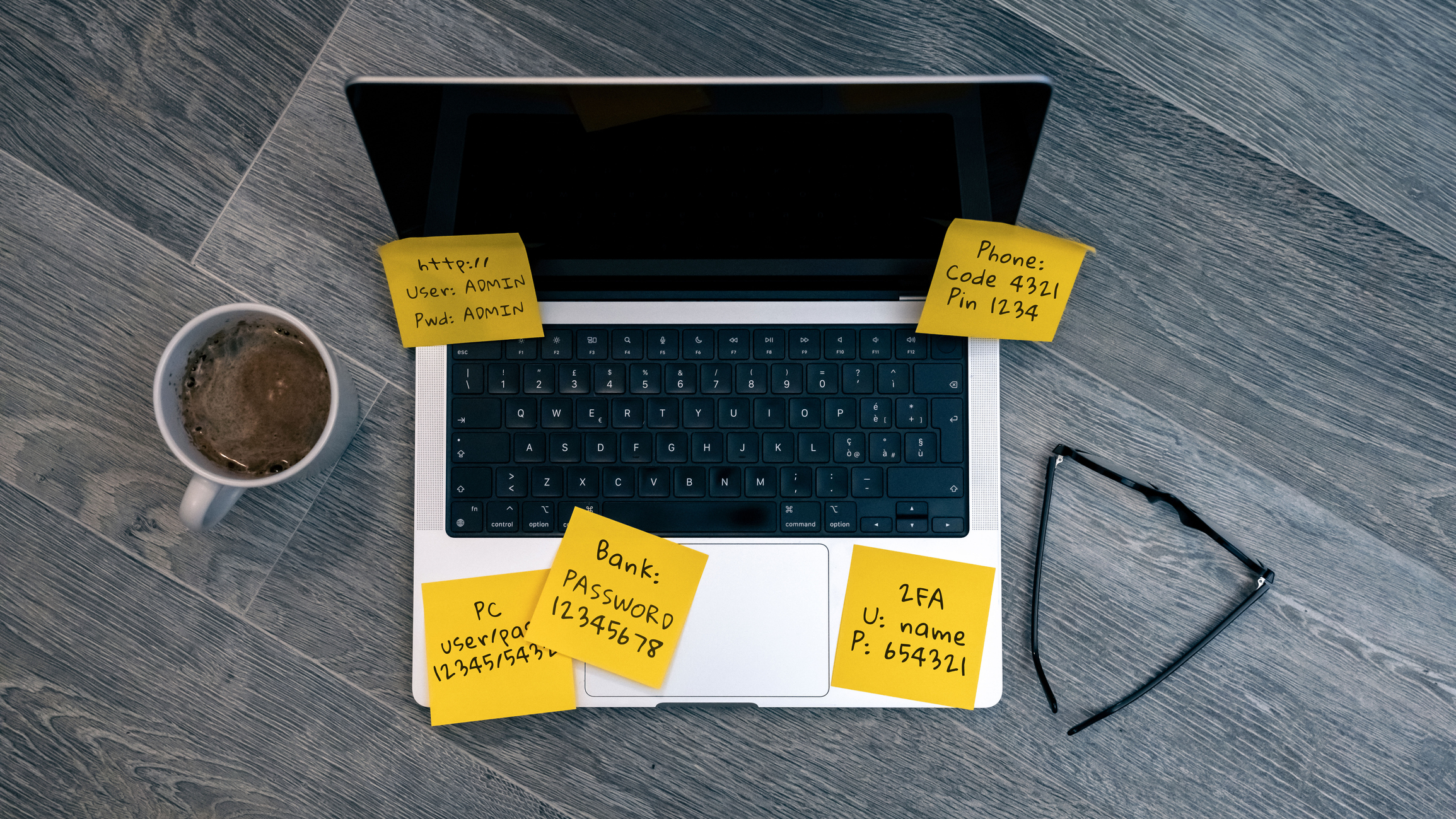 Unsecured Login Credentials and Private Pins Spread Across a Laptop Keyboard on Yellow Sticky Notes.