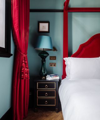 Blue bedroom, red drapes, red headboard and four poster bed