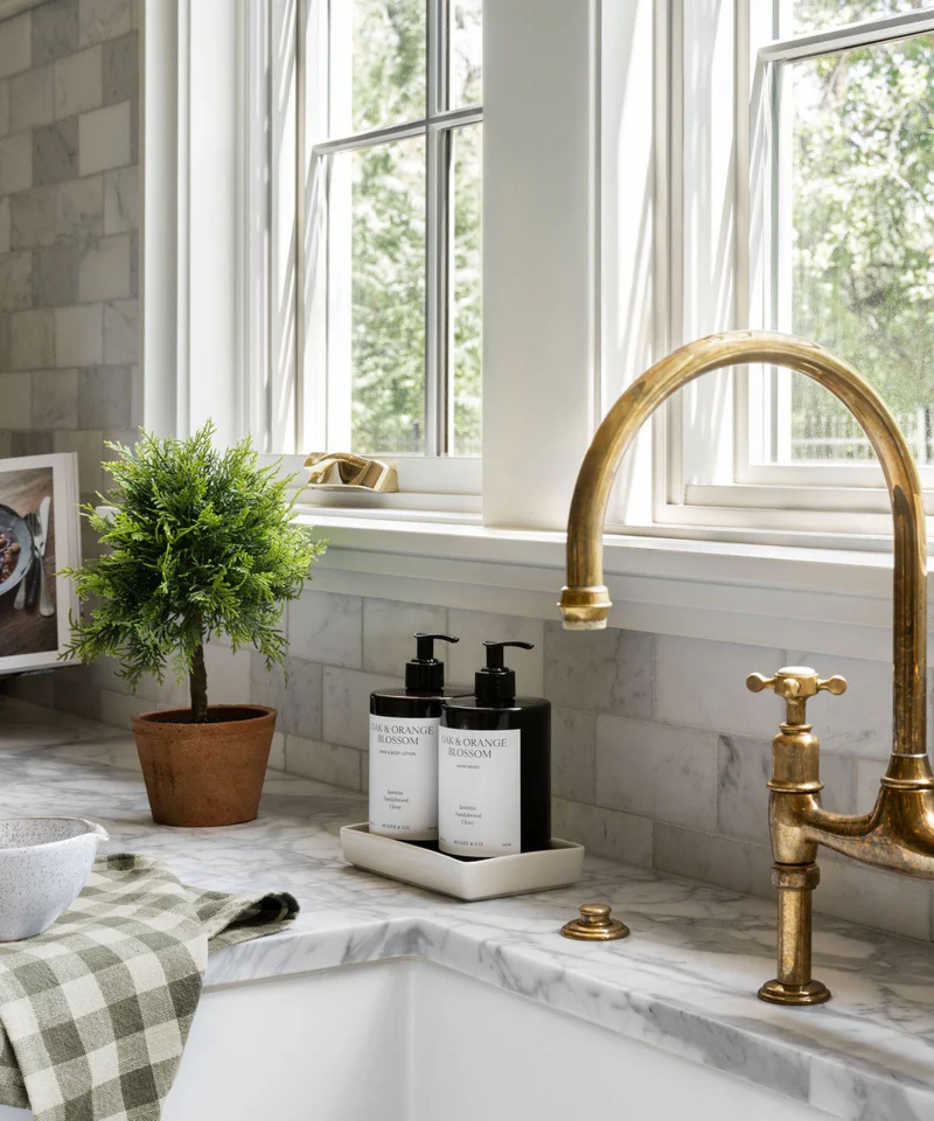 A neutral kitchen with marble countertops elevated with luxury soap bottles