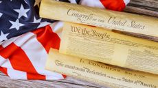 Historical documents representing founding principles of United States on flag backdrop