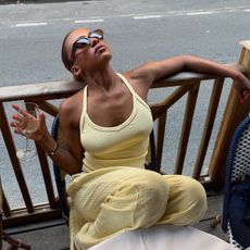 Influencer MV Tiangue wears a yellow racerback tank top and yellow linen trousers with brown sunglasses. 