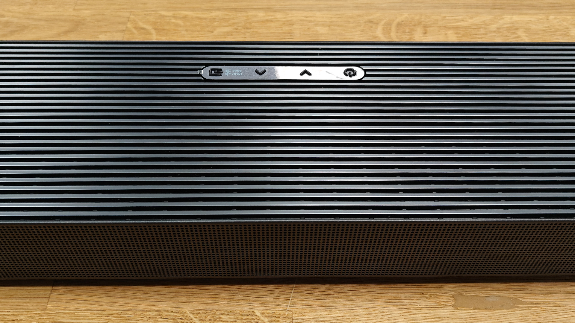 Samsung HW-QS700F Dolby Atmos soundbar on wooden surface detail of top grille