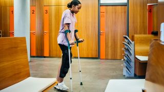 Injured Woman Walking With Crutches Through Hospital Reception