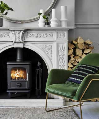 Morso 3112 wood burning stove with ornately designed fireplace and velvet green chair