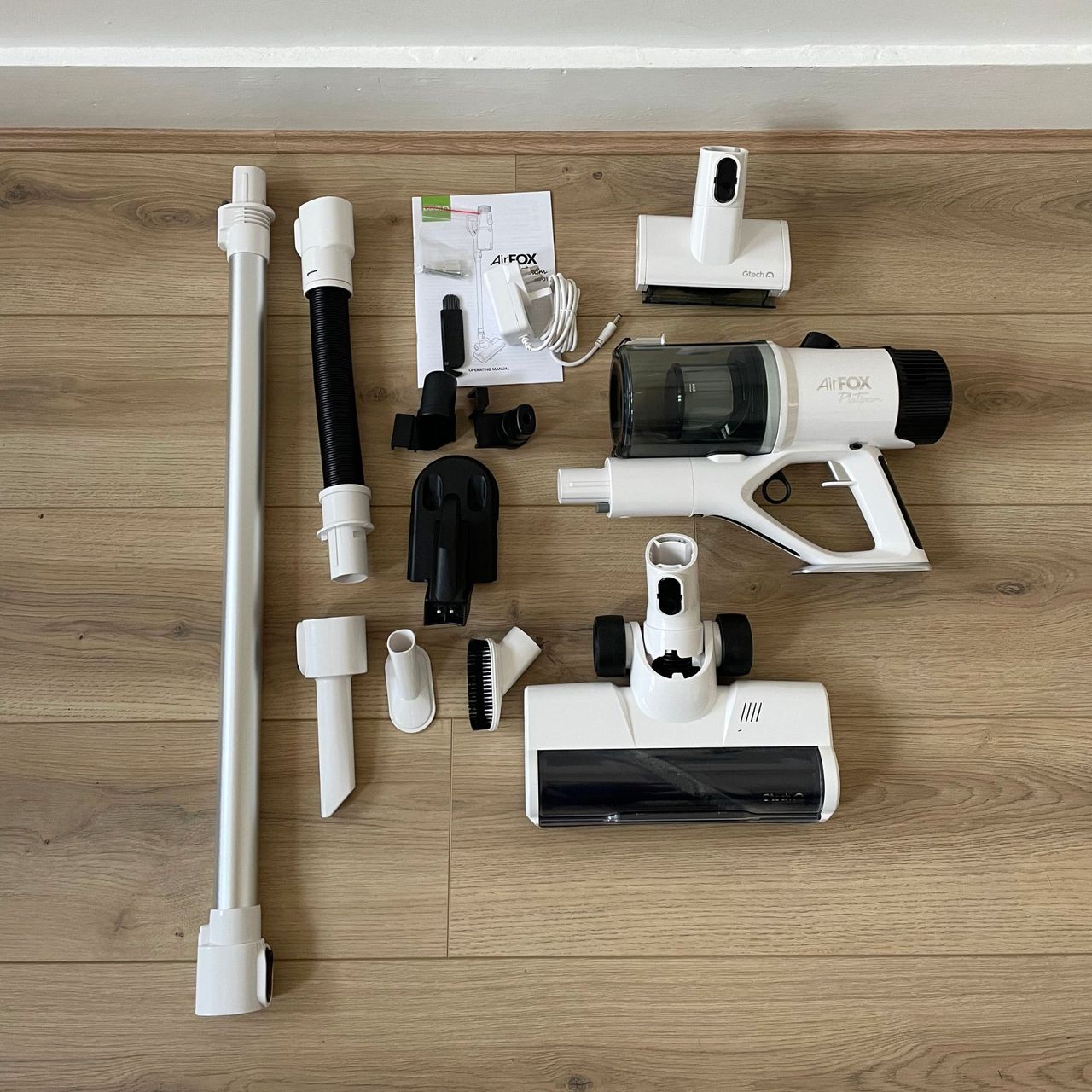 Gtech AirFOX Platinum Cordless Vacuum components laying on wood-effect hard flooring