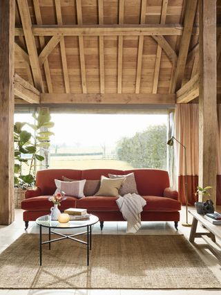 Two-tone curtains, and terracotta sofa in rustic barn style space, with jute rug.