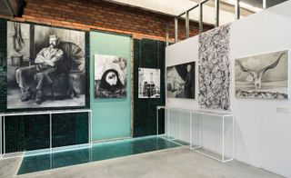 Photos and paintings hung on white, blue and brick wall