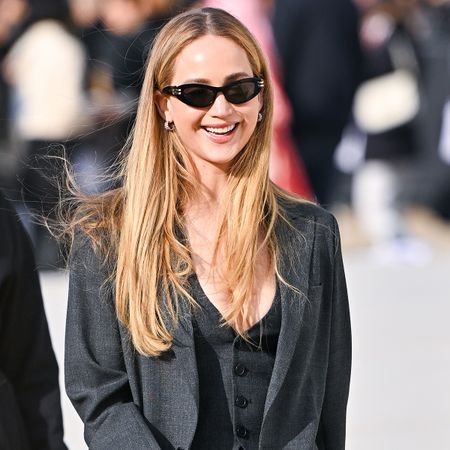 Jennifer Lawrence wearing a black hat, black sunglasses, a white t-shirt, and a black shoulder bag.