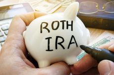 Hands holding piggy bank with Roth IRA. Pension plan.