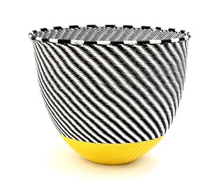 A black and white striped bowl with a yellow bottom made of telephone wire