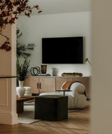 living room through an arched doorway with tv on the wall