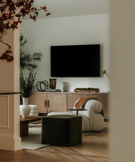 living room through an arched doorway with tv on the wall