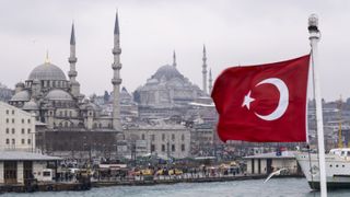 A harbour in Istanbul with the Turkish flag at the forefront.