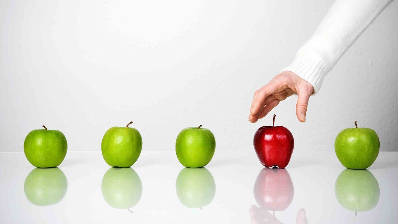 A person selecting one of five apples