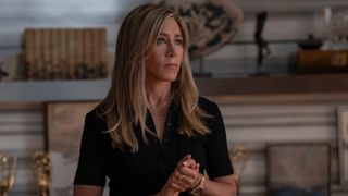 Jennifer Aniston as Alex in a black dress and looking serious in The Morning Show season 4 