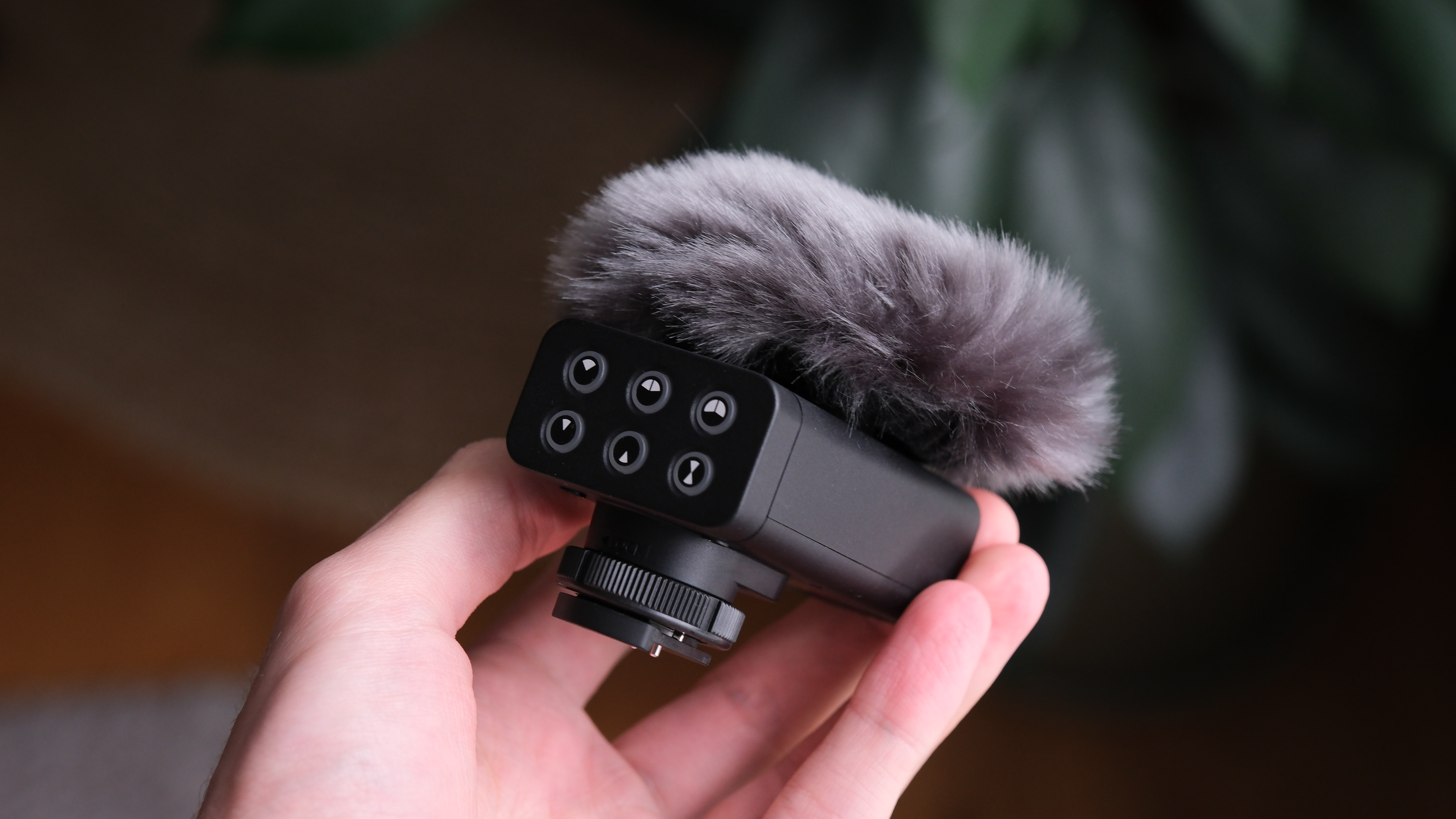 Panasonic Lumix DMW-DMS1 microphone held in hand with a furry windscreen attached, demonstrating its compact size.