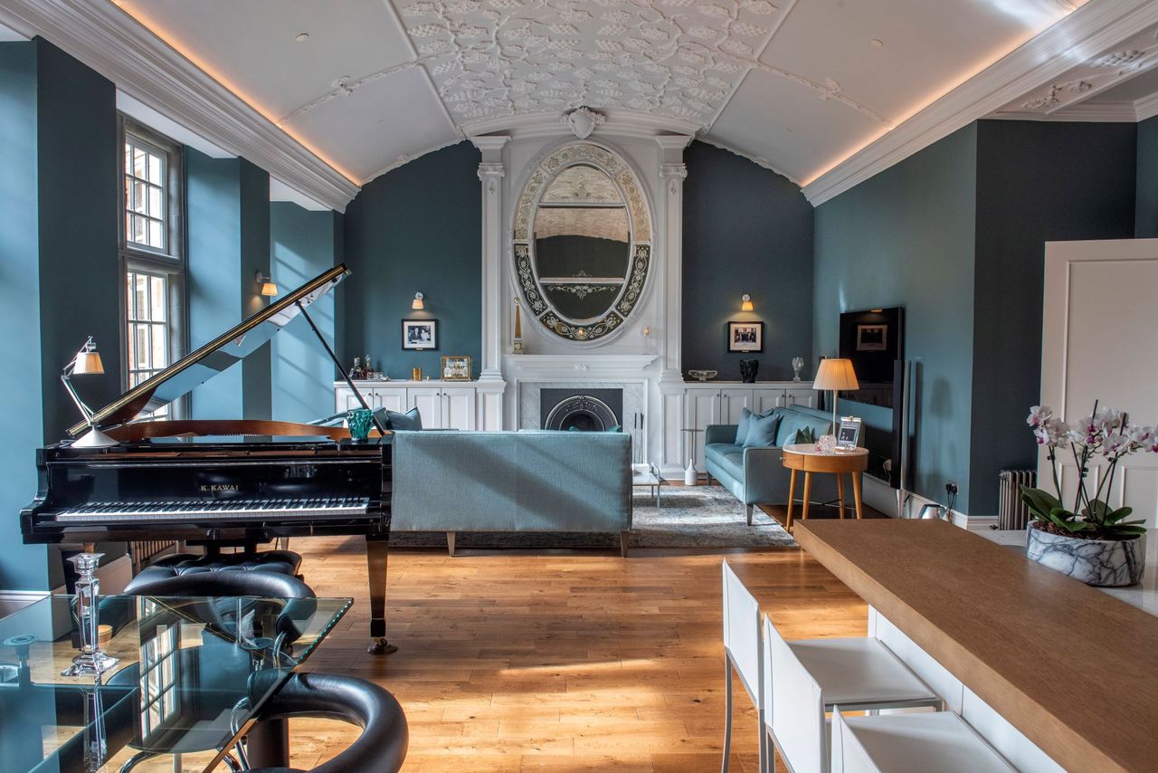 The kitchen-diner links to a living room which includes a black grand piano, a fireplace and wooden panelled flooring