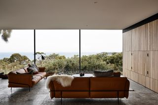 Large living room with glass windows and brown leather sofas