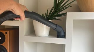 Detail tool on Miele Boost CX1 vacuum cleaner being used to clean shelving