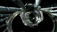 a hexagonal spacecraft floats away from a large metal ring on a black background